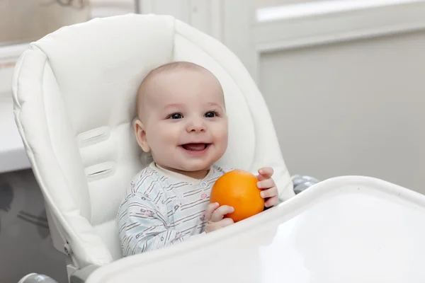 Смеющийся ребенок с апельсином — стоковое фото