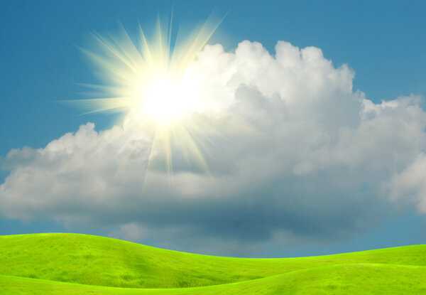 The sun in clouds in the blue sky and a green glade