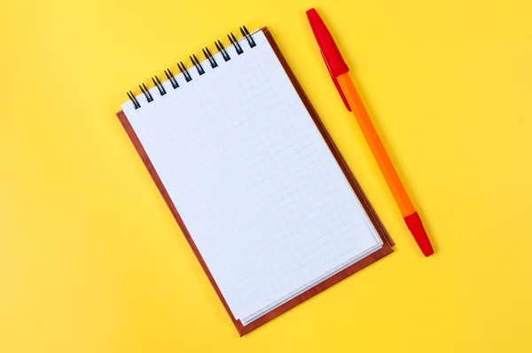 Блокнот и ручка на желтом фоне . — стоковое фото