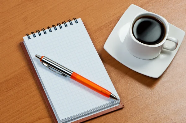 Notitieboekje met pen en koffie op tafel. — Stockfoto