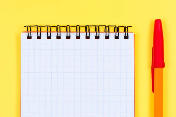 Notepad and ballpen on yellow background. Stock Photo