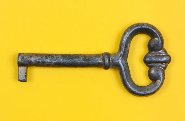 Antique key close-up on yellow background. — Stock Photo, Image