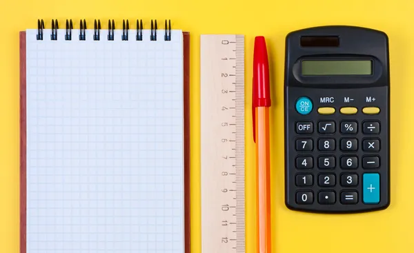 Notatnik, kalkulator i drewnianą linijkę z piórem. — Zdjęcie stockowe