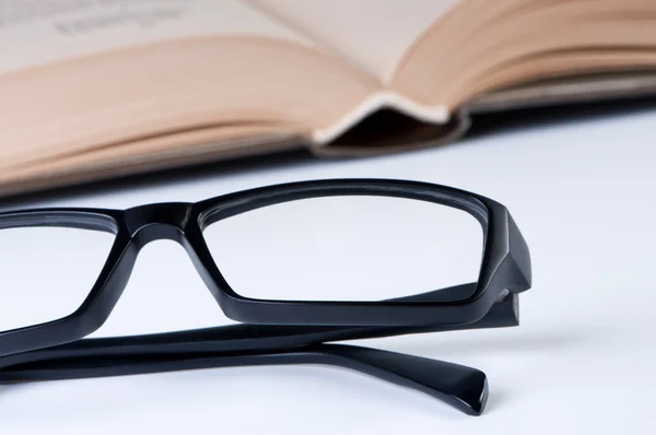 Läsglasögon på bakgrund av öppen bok. — Stockfoto