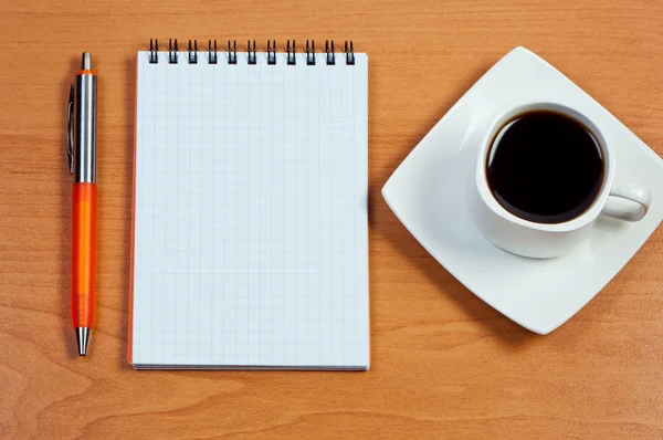 Pen, notebook and cup coffee on table. View from above. Royalty Free Stock Photos