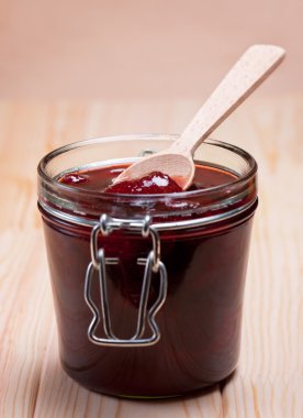 Strawberry jam in glass jar with wooden spoon. clipart