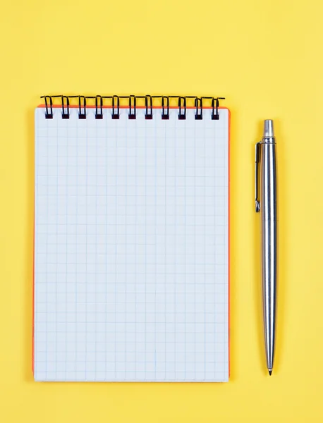 Caderno com caneta sobre fundo amarelo brilhante . — Fotografia de Stock