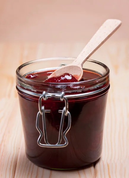 Strawberry jam in glass jar with wooden spoon. — Stock Photo, Image