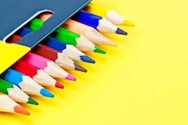 Låda med färgpennor på gul bakgrund. — Stockfoto