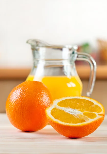 Апельсины с кувшином сока — стоковое фото