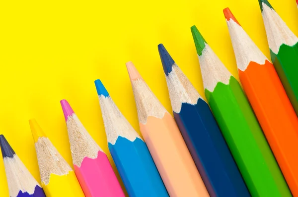 Разноцветные карандаши закрываются на ярко-желтом фоне — стоковое фото