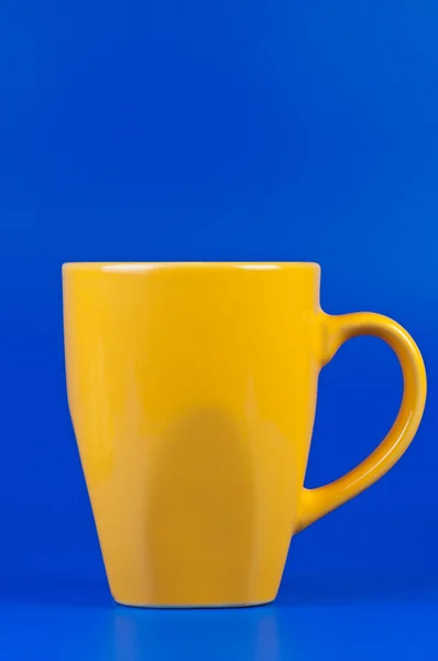 Желтая чашка на синем фоне . — стоковое фото