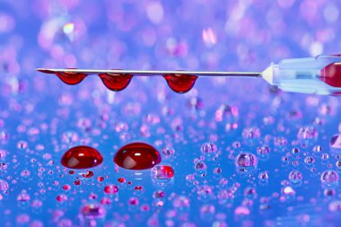 Syringe needle with fluid (blood) drops on droplets water backgr