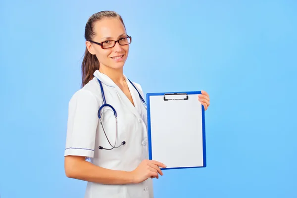 Young cute woman doctor holding copyspaced clipboard waist-high — Stock Photo, Image