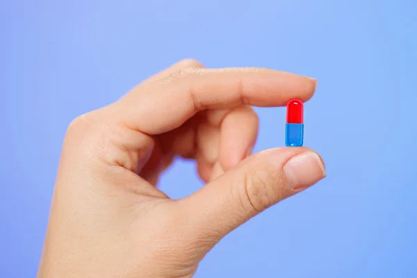 Bolus vermelho e azul (cápsula) na mão do médico, vista macro — Fotografia de Stock