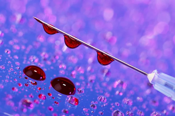 Syringe needle with fluid (blood) drops on droplets water backgr — Stock Photo, Image