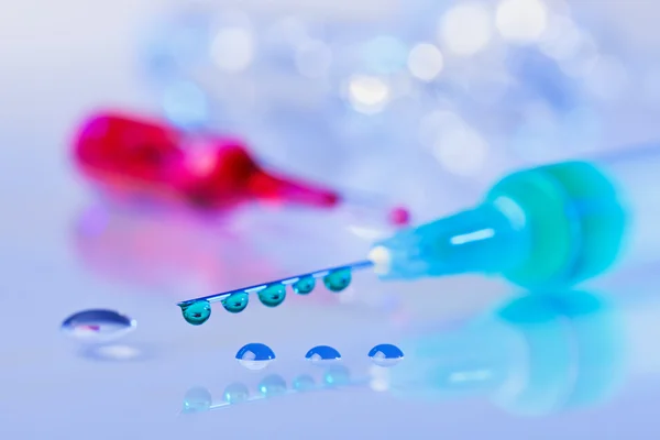 Syringe needle with green fluid drops on droplets water backgrou — Stock Photo, Image