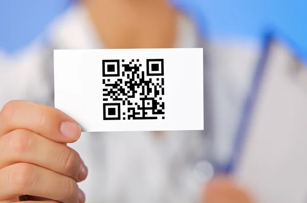 Médico segurando cartão de visita com cuidados de saúde QR código em azul — Fotografia de Stock