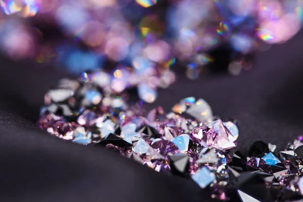 Diamond (small purple jewel) stones heap over black silk cloth b — Stock Photo, Image