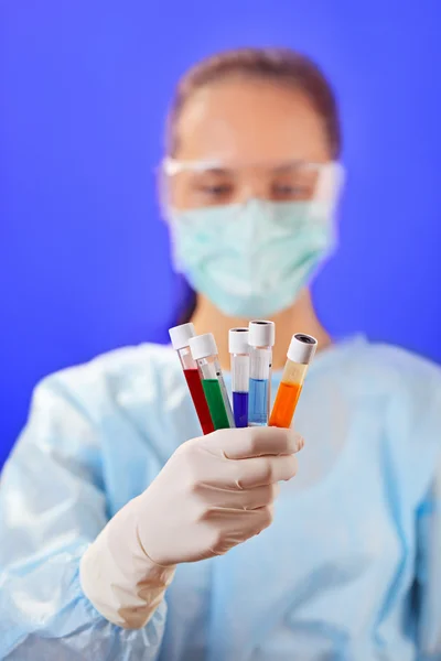 Doctor (woman) analyzing medical test tubes on blue background — Stock Photo, Image