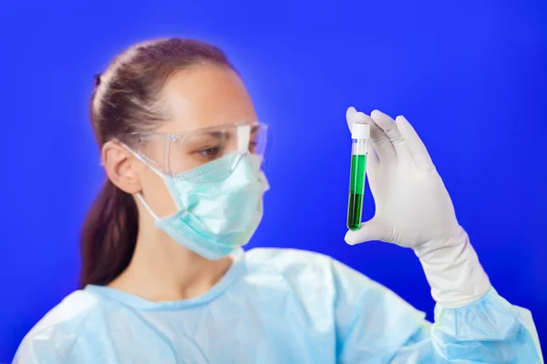 Médico (mujer) analizando tubos de ensayo médicos sobre fondo azul — Foto de Stock