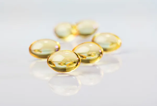 Pillole (capsule) di olio di fegato di merluzzo, macro vista sul bianco — Foto Stock