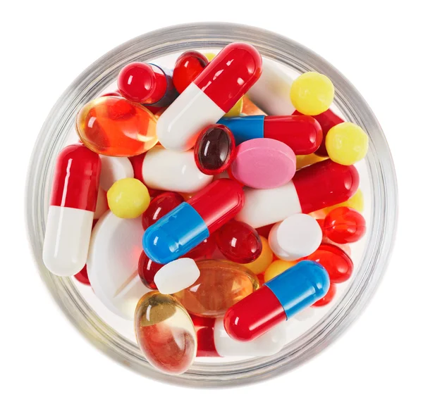 Píldoras, tabletas y medicamentos amontonan en un recipiente de vidrio aislado en blanco —  Fotos de Stock