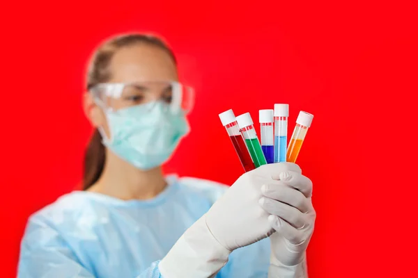 Médecin (femme) analysant des éprouvettes médicales sur fond rouge — Photo