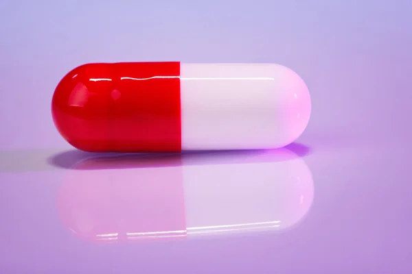 Красно-белый болюс (капсула) на фиолетовый, макровид — стоковое фото