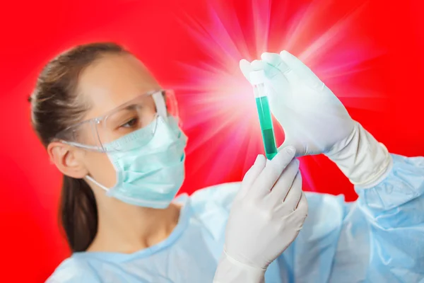 Médico (mujer) analizando tubos de ensayo médicos sobre fondo rojo — Foto de Stock