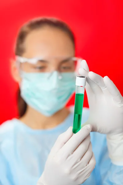Médico (mulher) analisando tubos de ensaio médicos em fundo vermelho — Fotografia de Stock