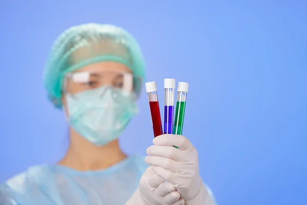 Zkumavky lékařské vzorky v rukou lékaře na modrém pozadí — Stock fotografie