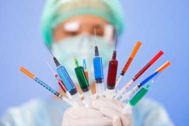 Young woman doctor with many multicolor syringes in hands on blu clipart