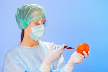 genç kadın doktor ile mavi şırıngayı turuncu meyve enjekte