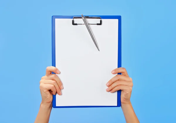 Clipboard in female hands on blue background — Stock Photo, Image
