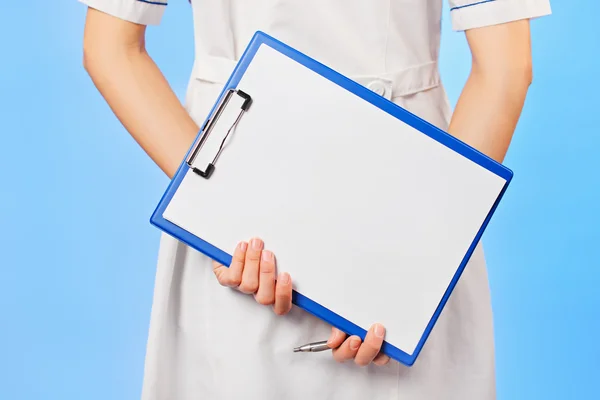 Doctor with copyspaced clipboard waist-high portrait on blue — Stock Photo, Image