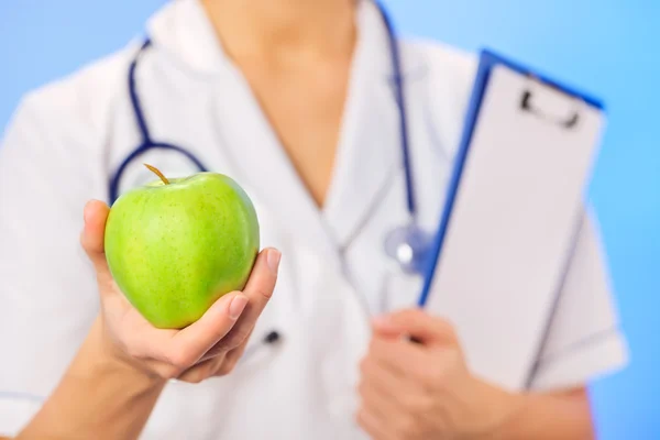 Médico (mujer) sosteniendo manzana verde con espacio de copia en azul —  Fotos de Stock