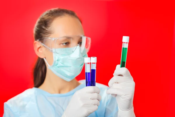 Doctor (woman) analyzing medical test tubes on red background — Stock Photo, Image