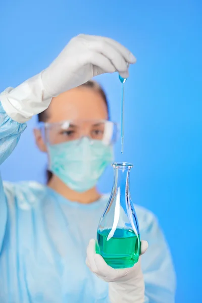 Mujer joven médico haciendo análisis con tubo de ensayo en azul — Foto de Stock