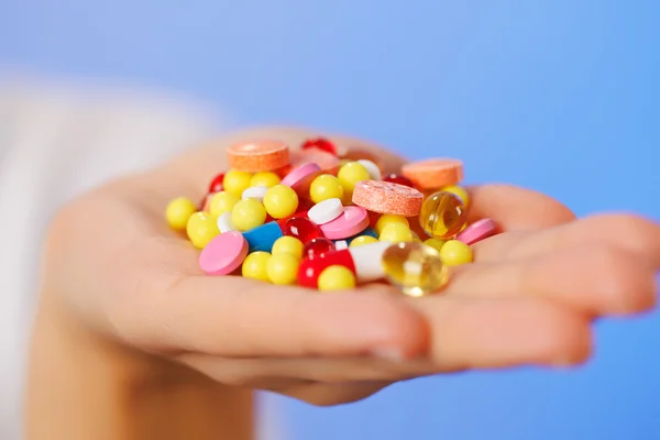 Pilules, comprimés et médicaments entassés dans la main du médecin sur le fond bleu — Photo