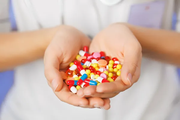 Δισκία, χάπια και φάρμακα σωρού στο χέρι του γιατρού στο μπλε αμουδερές — Φωτογραφία Αρχείου