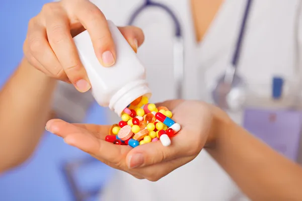 Comprimidos, comprimidos e drogas derramando de garrafa na mão do médico em — Fotografia de Stock