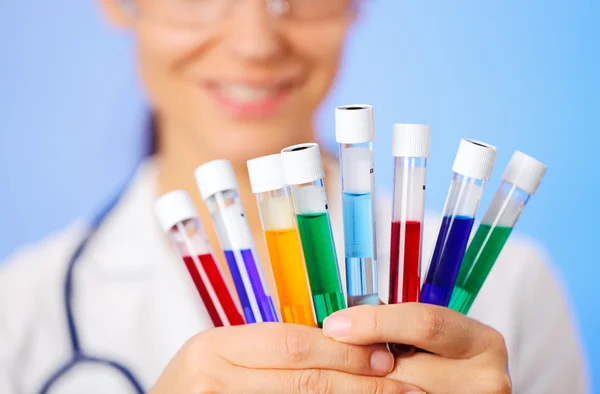 Tubos de ensaio médicos multicoloridos com amostra de fluido nas mãos do médico — Fotografia de Stock