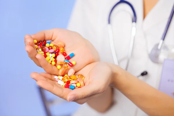 Comprimidos, comprimidos e drogas derramando nas mãos do médico em azul backg — Fotografia de Stock