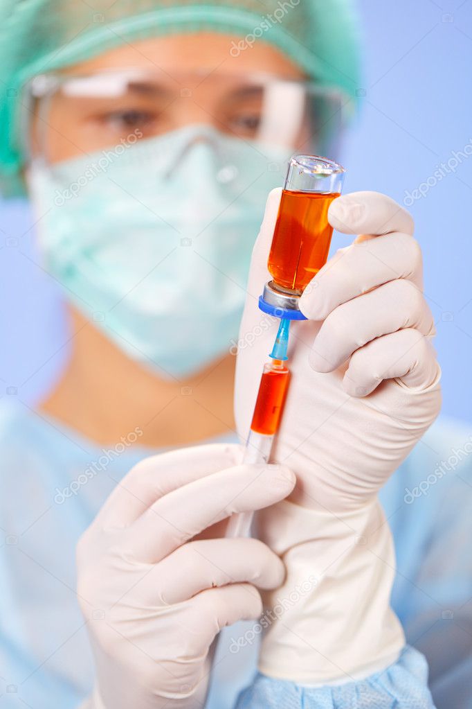 Young woman doctor preparing injection with ampoule and syringe