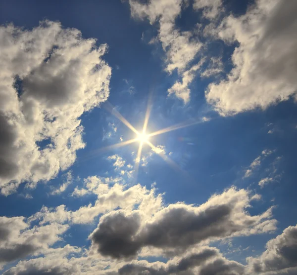 Сяюче сонце в темно-синьому небі з хмарами — стокове фото