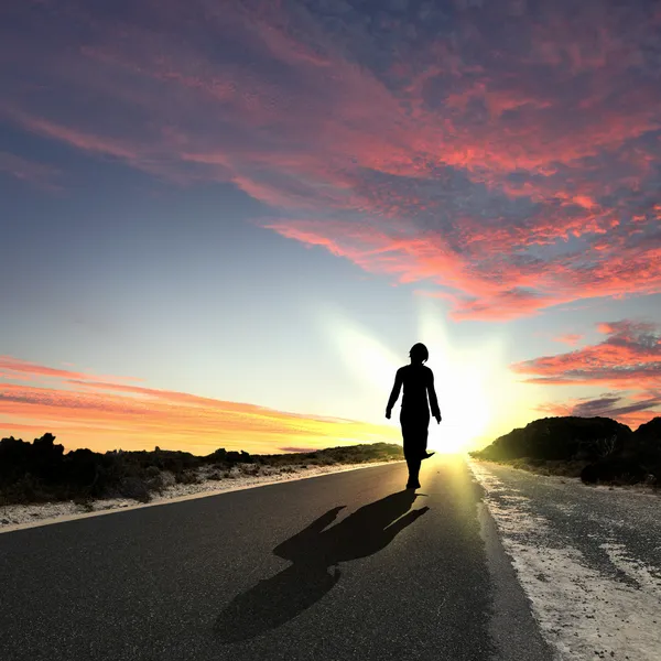 Hombre alejándose al amanecer a lo largo del camino — Foto de Stock