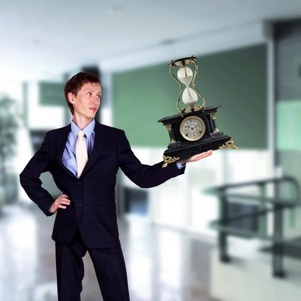 Бизнесмен в офисе держит пирамиду часов — стоковое фото