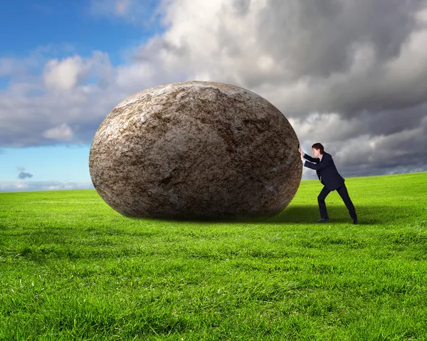 Empresário rolando uma pedra gigante — Fotografia de Stock