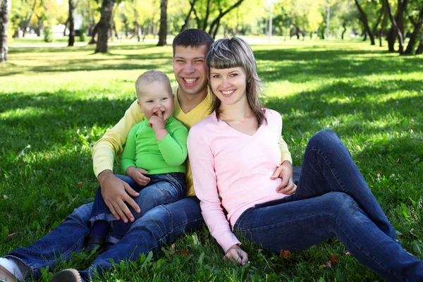 Família jovem com uma criança no parque de verão — Fotografia de Stock